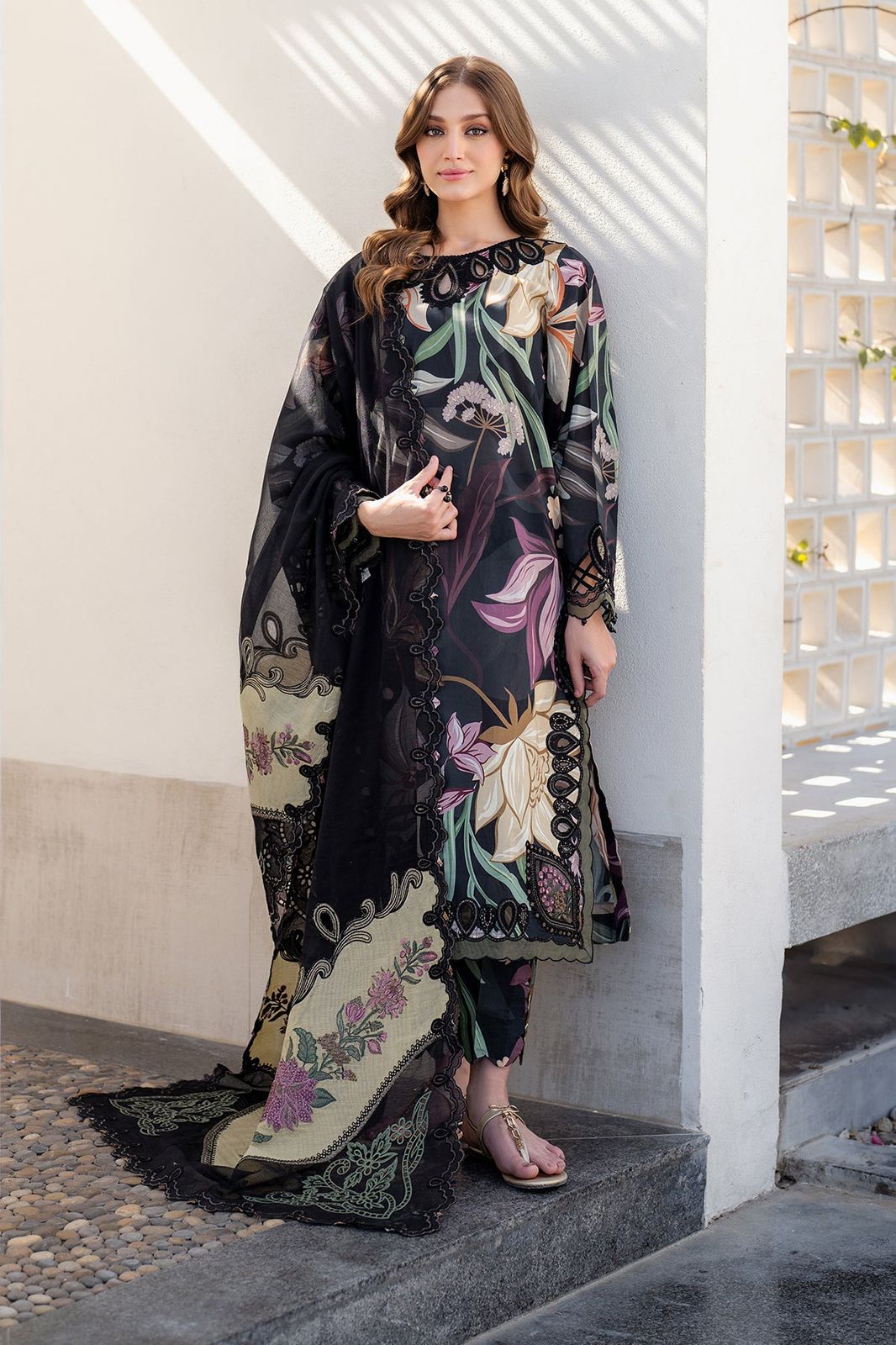 Woman wearing a black floral embroidered outfit standing on steps.