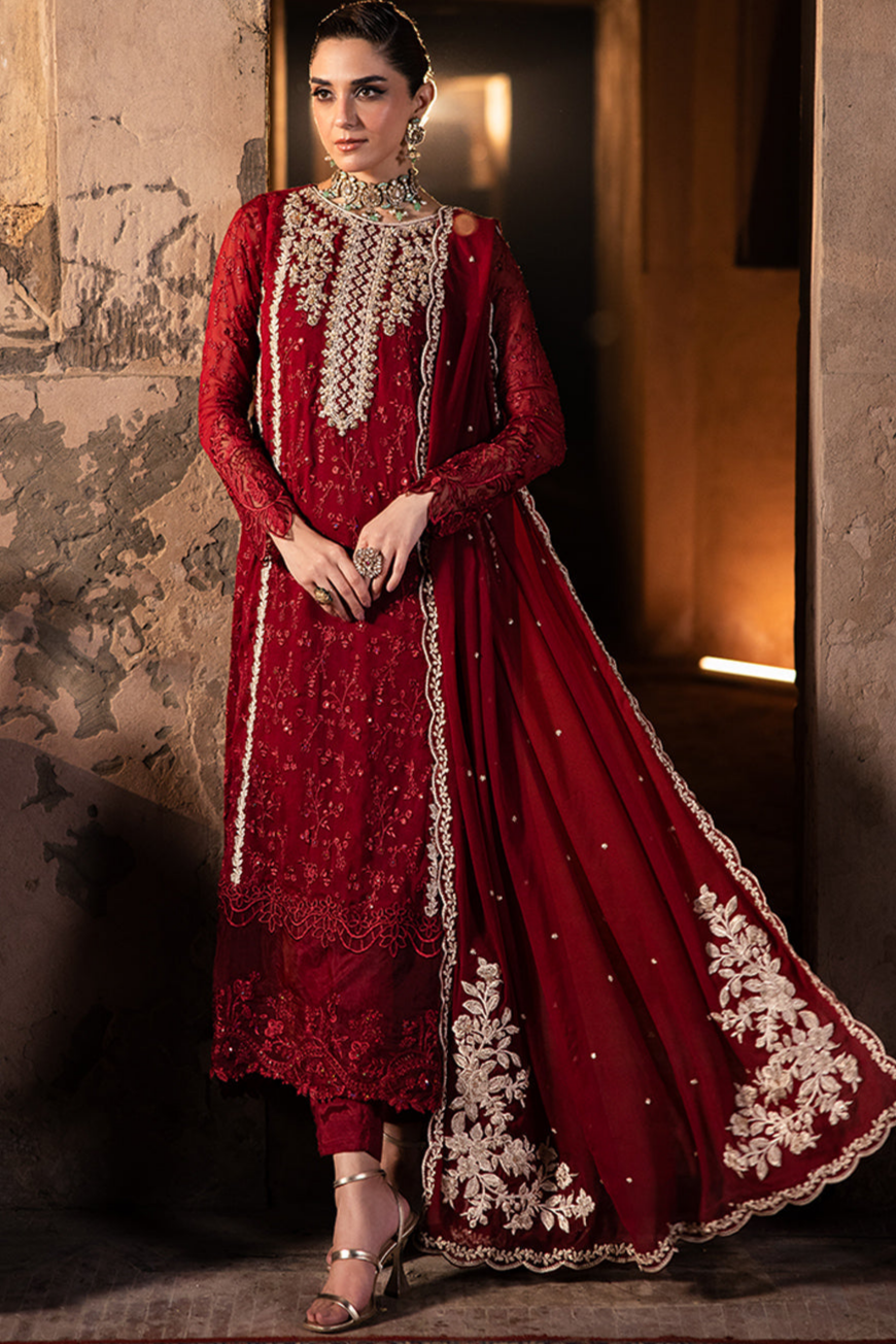 Red traditional outfit with intricate white embroidery on a textured wall background