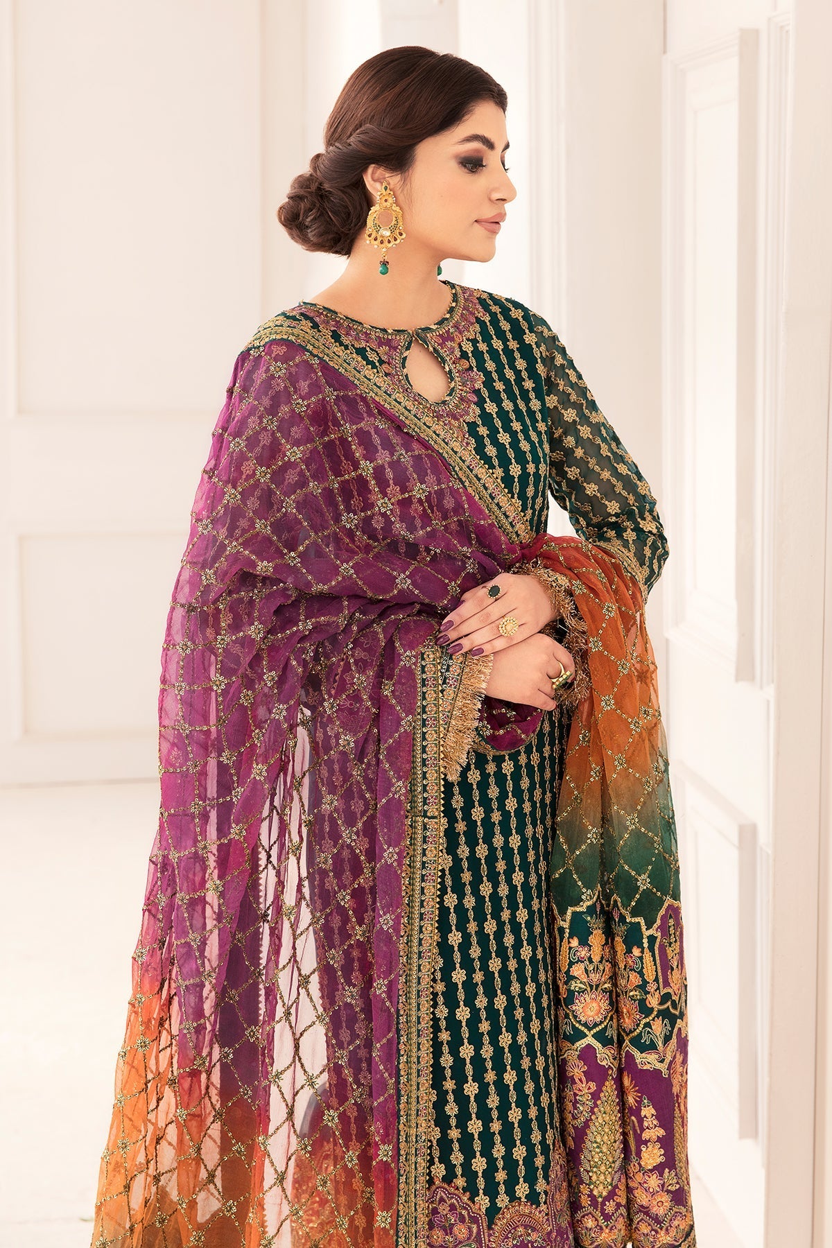 Woman wearing a colorful traditional outfit with a purple dupatta against a white background
