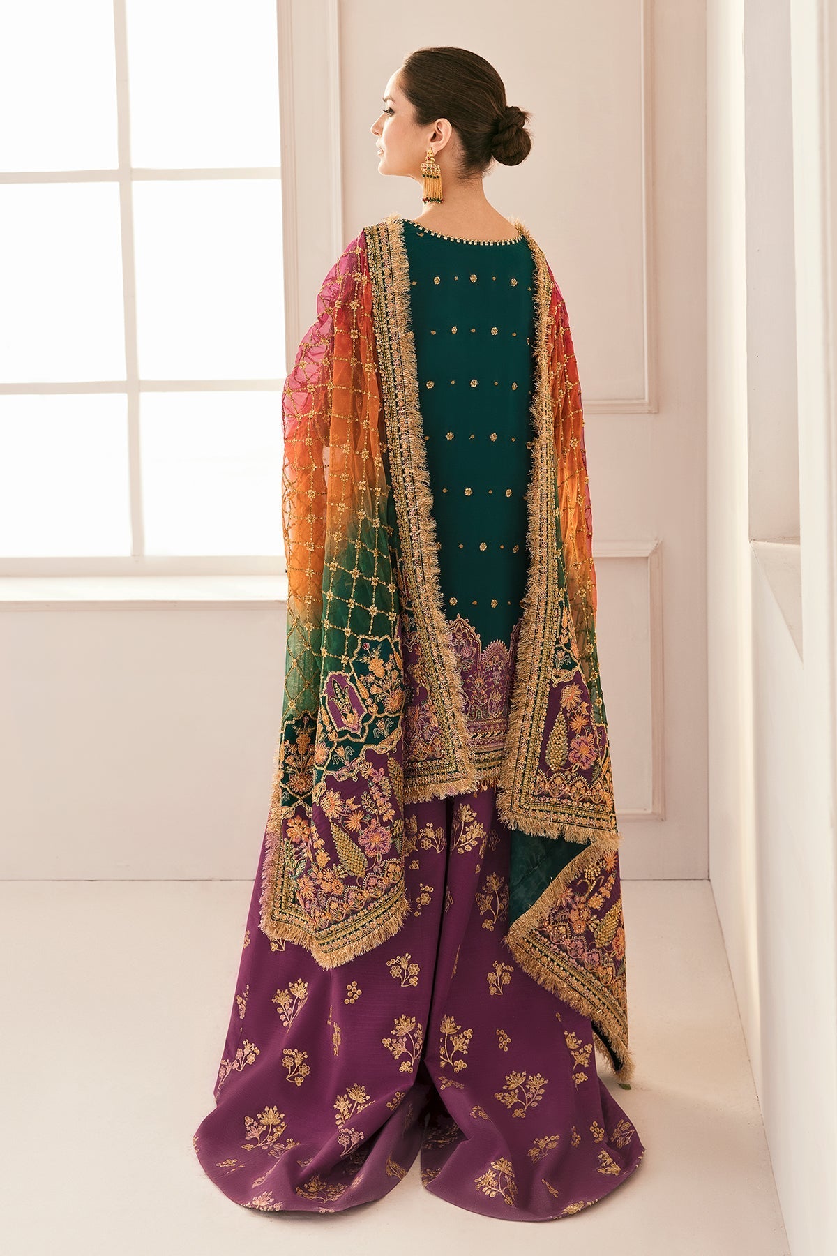 Woman wearing a traditional outfit with a colorful dupatta in a minimalistic setting