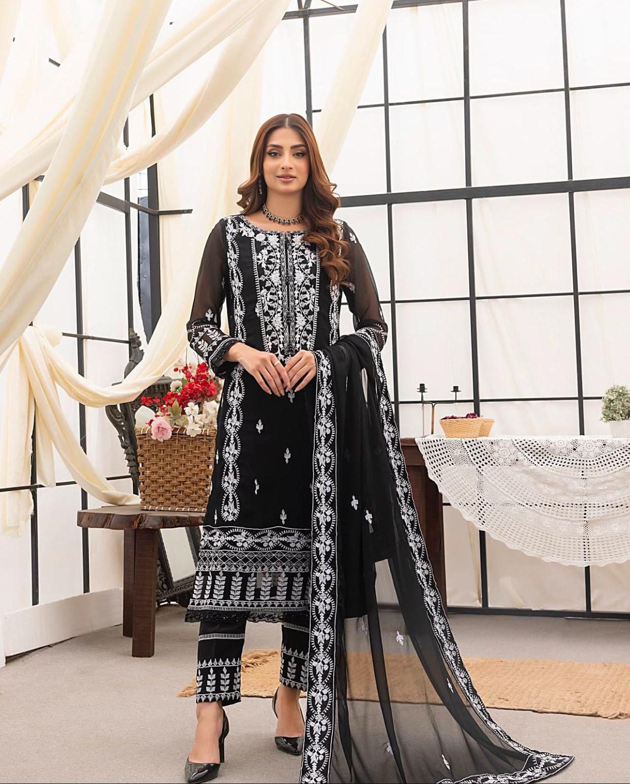Woman wearing a black and white embroidered outfit in a modern room setting.